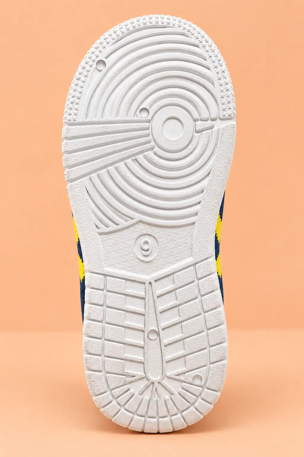 Non-slip white sole of navy blue kids shoes with circular grip tread pattern