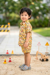 Close-up of construction vehicle print on mustard yellow cotton fabric — JCB digger excavator kids coord set