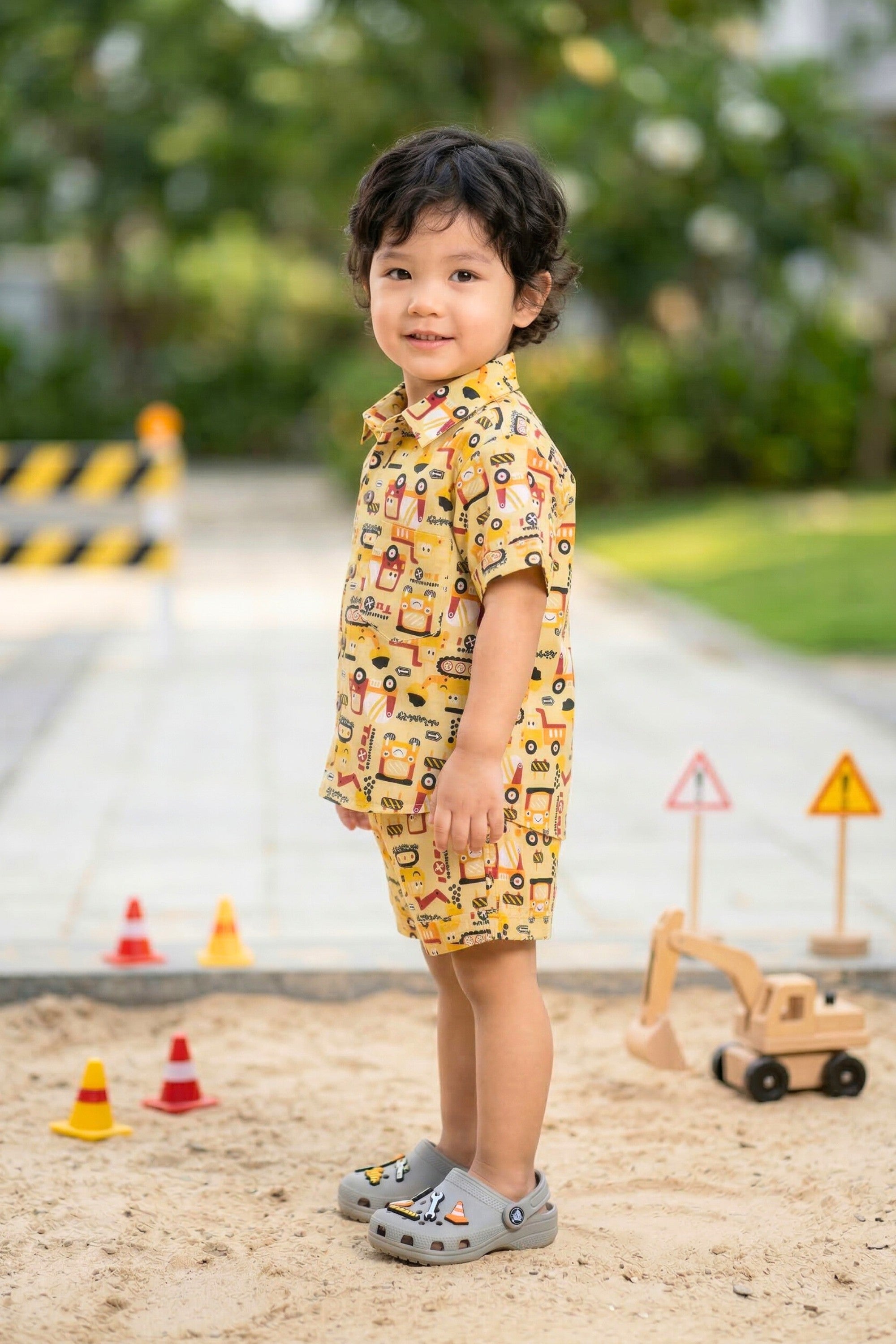 Close-up of construction vehicle print on mustard yellow cotton fabric — JCB digger excavator kids coord set