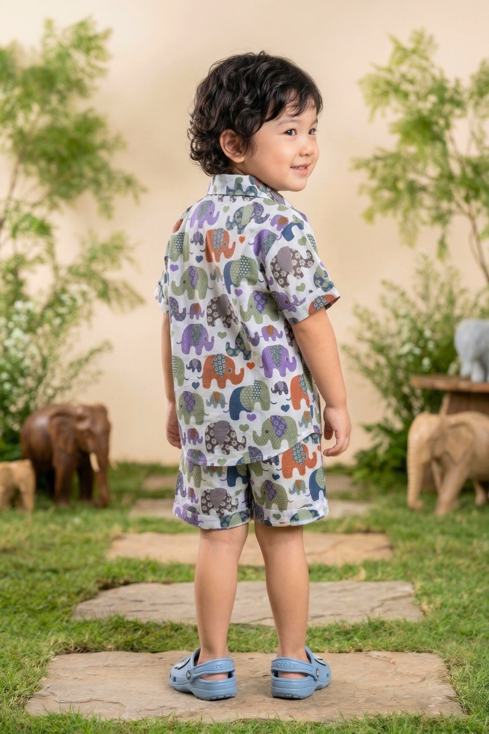 Detail view of the multicolour elephant parade print on the Bebe Unicorn boys white coord set — patchwork illustrated elephants in purple, orange, teal, navy, olive and grey, each with unique floral, diamond and dot body patterns, with hearts scattered throughout on 100% cotton fabric for children aged 2–8 years.