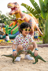 Flat lay of the Bebe Unicorn Boys Colorful Dinosaur Adventure Coord Set — playful casual wear with bright red, yellow & green cartoon dinosaurs on white base, classic collar shirt with chest pocket and matching shorts with side pockets. Perfect for outdoor play, summer vacation, park adventures, and everyday wear. 100% cotton, dermatologist tested, made in India. ₹699, sizes 2–8 years.
