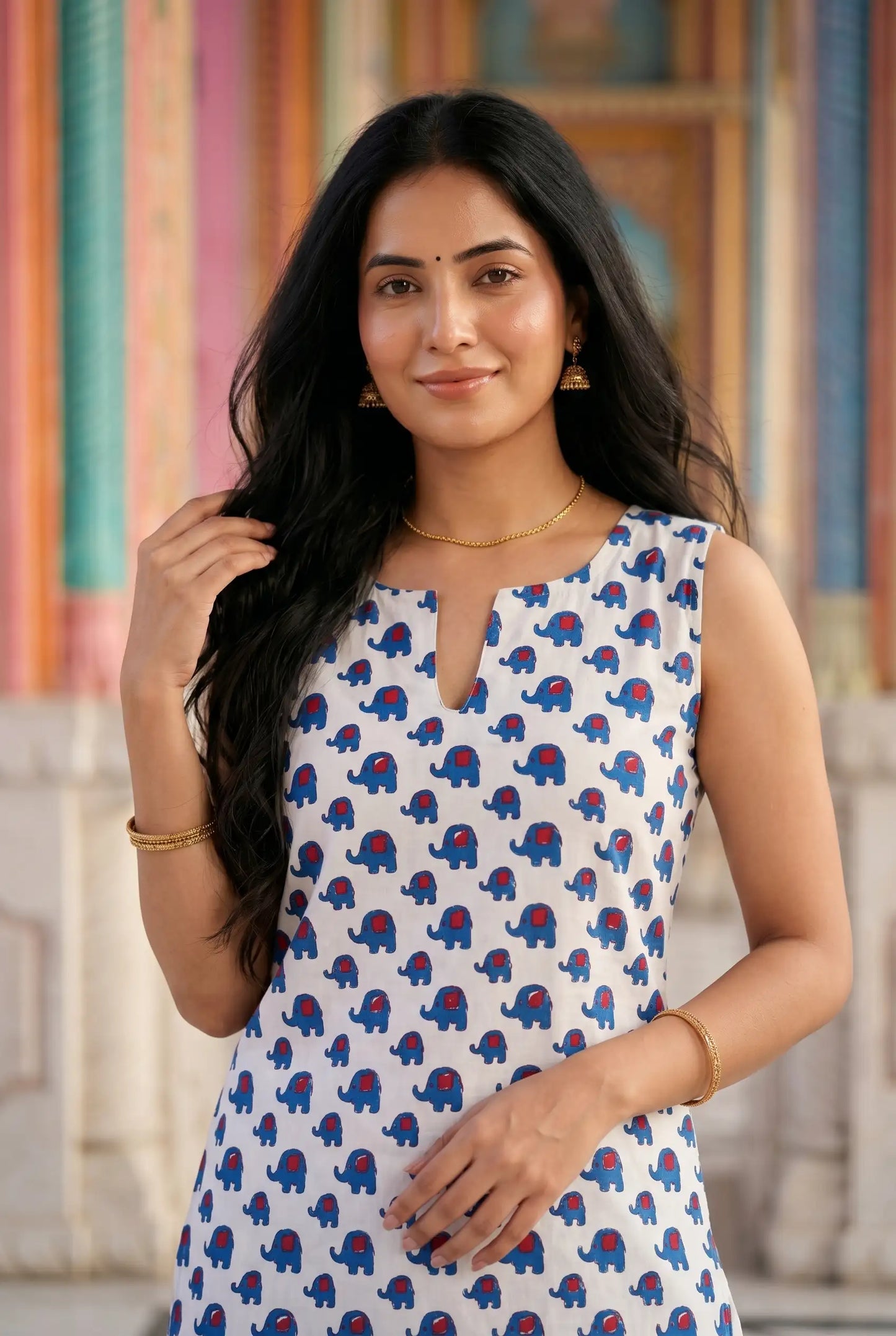 Close-up of elephant print kurta featuring blue and red motif on white cotton with V-neckline and gold chain necklace