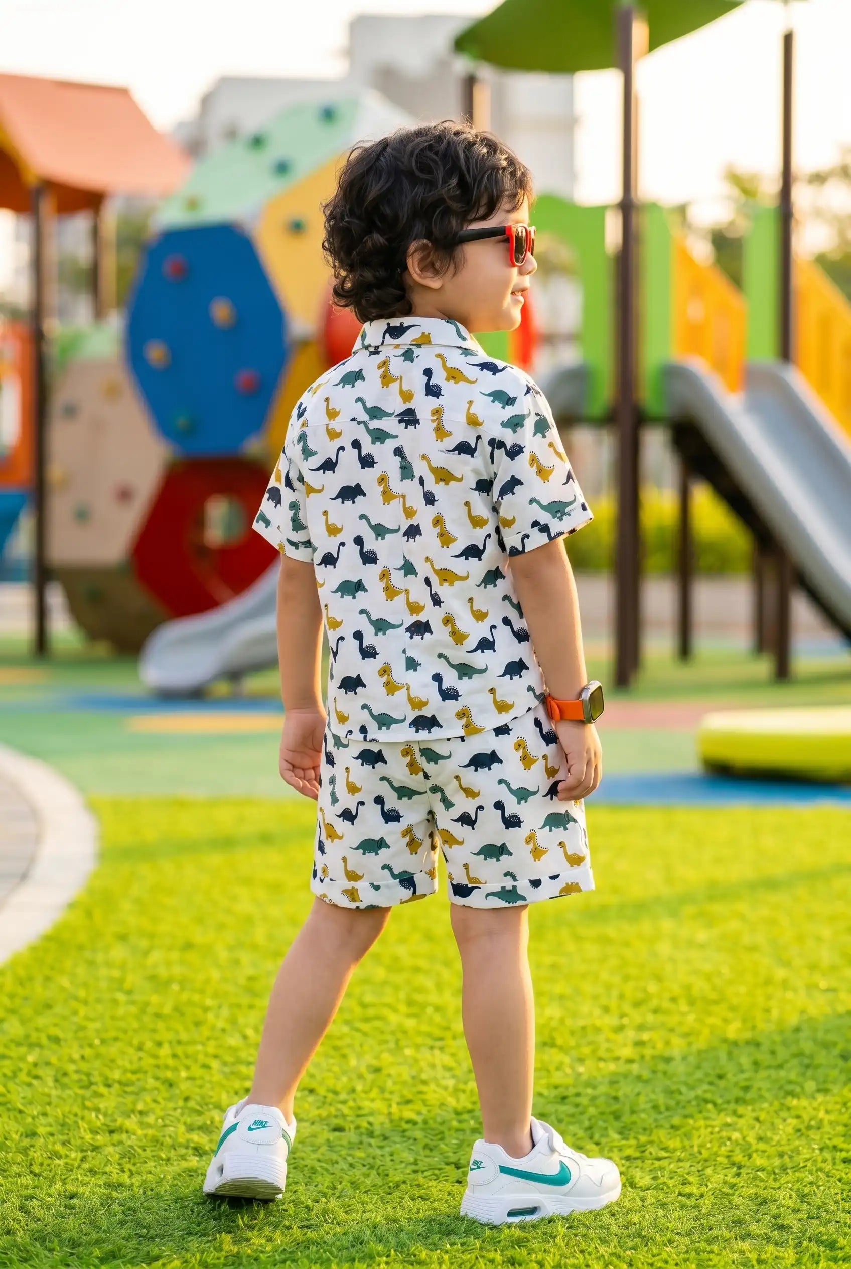 Detailed view of colorful dinosaur print on boys casual shirt, T-Rex Triceratops long-necks on white cotton, playful kid design