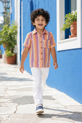 Boy wearing orange and purple zig-zag shirt with white trousers, front view