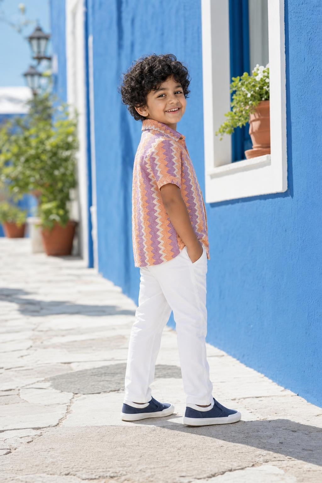 Side view of boys orange and purple zig-zag shirt styled with white trousers