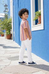 Side view of boys orange and purple zig-zag shirt styled with white trousers