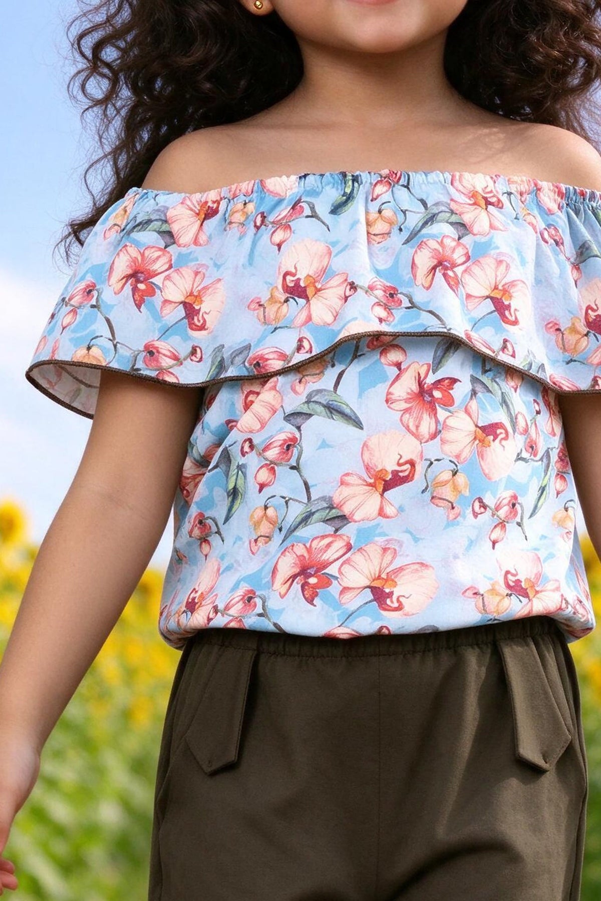Close-up of girls off-shoulder orchid print ruffle top and olive pants