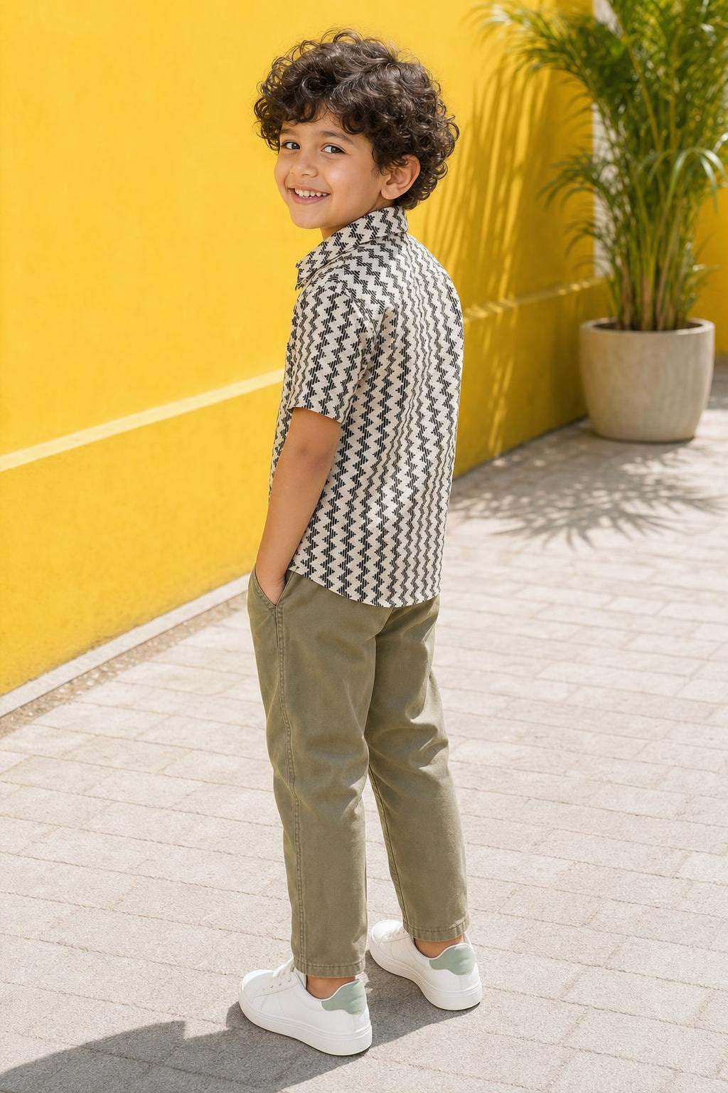 Side view of boys black and cream zig-zag print shirt styled with sage green chinos